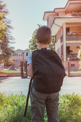 schoolboy comes back to school. Behind shoulders at the pupil a satchel.Back view