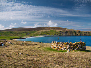 With sunshine on turquoise water and an old stone enclosure (a planticrub) on the right, the...