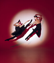 Fototapeta na wymiar Ballet dancers dancing over red studio background. Modern design. Contemporary colorful conceptual light as rising sun at Japan.