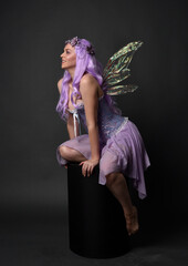 Full length portrait of a purple haired  girl wearing fantasy corset dress with fairy wings and...