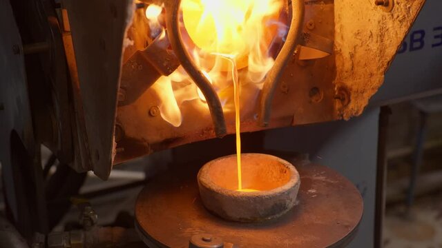 Close up at the molten silver pouring into the smelter bowl at the plant for production items out of silver