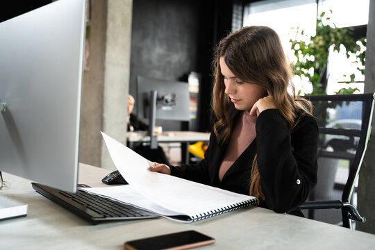 Design and architecture theme. A female young architect is working on a project with blueprints at the computer in a modern office. Architect engineer woman working plan at counting room