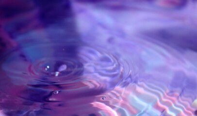 Naklejka na ściany i meble Wallpapers. Frozen movement of water. Drops of water falling and splashing. Sparkles, reflections of light. Violet/pink color.