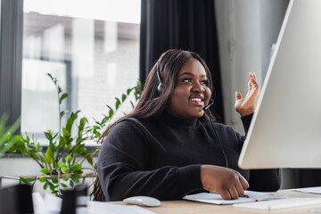 smiling african american plus size operator in headset with microphone in office.