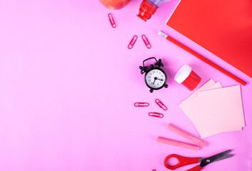 Back to school flat lay background. Set of stationery supplies and alarm clock on pink with copy space