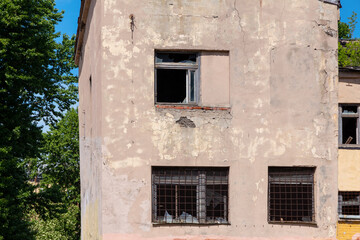 The facade of an old settled and abandoned residential city building with broken windows