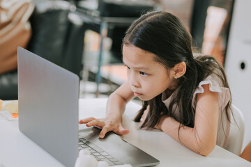 Asian girl is trying to do exam online with laptop at home.