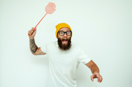 Young caucasian hipster man holding a fly swatter wanting to kill annoying mosquito or a fly.