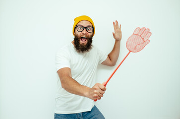 Young caucasian hipster man holding a fly swatter wanting to kill annoying mosquito or a fly.