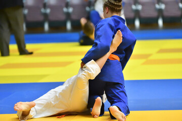 Naklejka premium Two Girls judoka in kimono compete on the tatami 