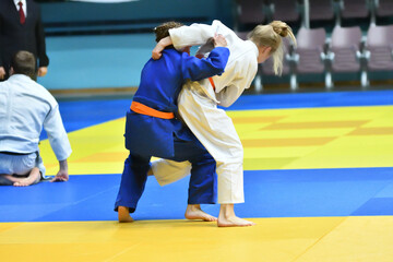 Naklejka premium Two Girls judoka in kimono compete on the tatami 