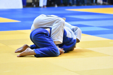 Two Girls judoka in kimono compete on the tatami 