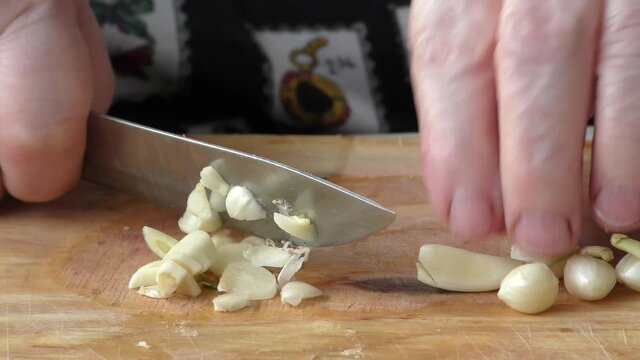 Homemade food preparation process.  The cook cuts the garlic with a knife.  Healthy food concept