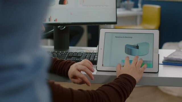 Focused invalid woman employee with locomotor disabilities using digital tablet checking company project working in business start-up office sitting in wheelchair. Busy multitasking african employee