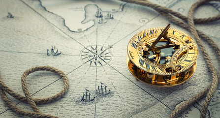 Magnetic old compass  and rope on vintage world map. Travel, geography, navigation, tourism and exploration concept wide background. Macro photo. Very shallow focus.