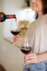pouring red wine into glasses in female hands