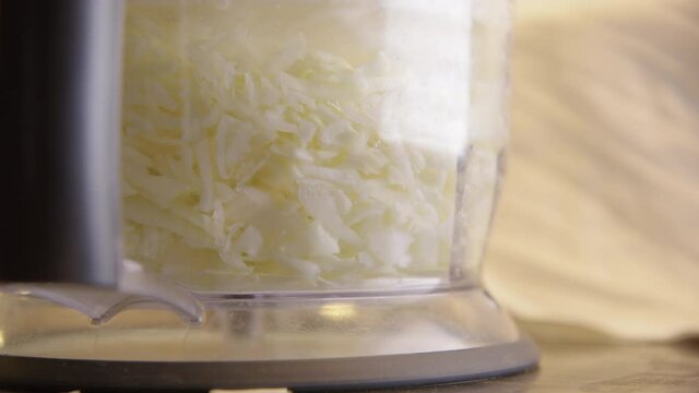 SAUERKRAUT - Food processor shredding cabbage, close up