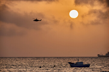 helicopter flight over the sea at sunset with watercraft in the sea