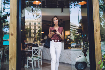 Stylish woman with notepad leaving modern cafe