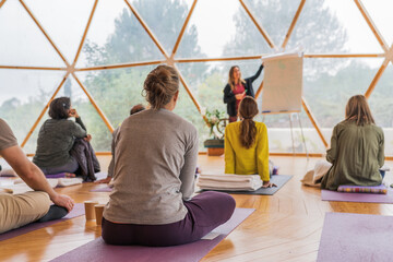 People sitting and listening to trainer near marker board in light room