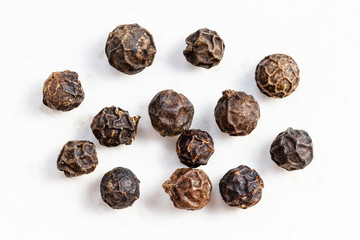 several black pepper peppercorns close up on gray