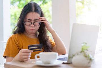 Stressed of  freelance people business female casual show holding a credit card having a headache working with laptop computer in coffee shop like the background,for online shopping and payment