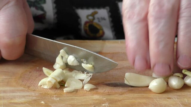 Homemade food preparation process.  The cook cuts the garlic with a knife.  Healthy food concept