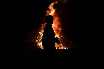 Silhouettes of a boy with a camera on the background of fire