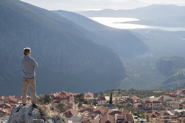 Tourist on the top of the hill in Greece, Delphi with the view of sea bay among the rocks