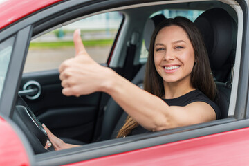 Obraz na płótnie Canvas Car. Beautiful woman in the car shows thumbs up. Happy brunette in the car.