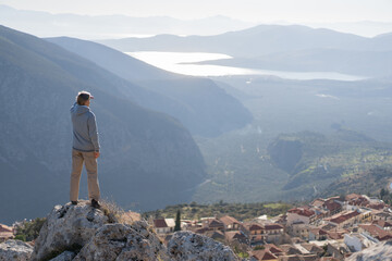 Tourist on the top of the hill in Greece, Delphi with the view of sea bay among the rocks