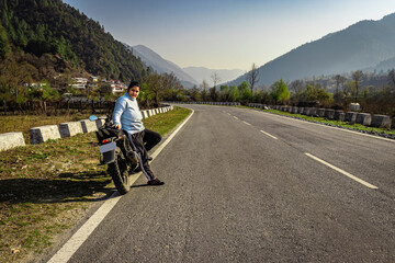 Fototapeta premium girl sitting at motorcycle at tarmac road with beautiful natural view at morning