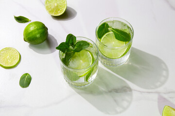 A  two glasses with mojito on light stone background. Fresh cold refreshing summer cocktail with lime, mint and ice. 