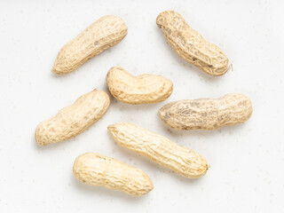 several whole peanuts close up on gray