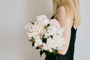 Naklejka premium A rich bouquet with peonies in the hands of a girl on a light background. Romantic festive bouquet. Fresh floral. A holiday gift. Beautiful white flowers. The florist girl gathered a bouquet