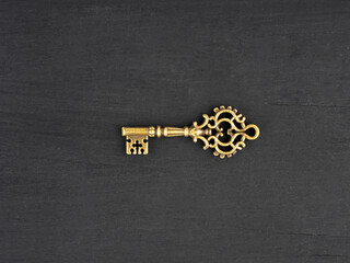 Obraz premium Bronze color antique key on black wooden background