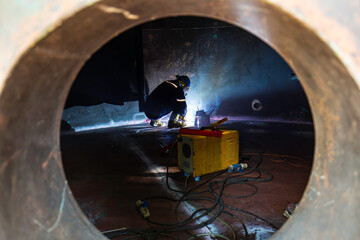 Male worker wearing protective clothing and repair welding sparks industrial construction tank oil...