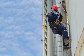 Male worker rope access height safety inspection of thickness storage oil and gas tank