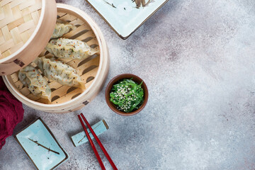 Bamboo steamer with panasian dumplings, horizontal shot over beige metal background with copyspace, above view