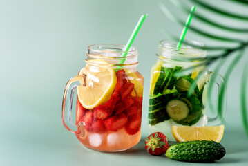 Variety of Cold Summer Drinks in Glass Jars Infused Detox Water with Cucumber Lemon and Strawberry Healthy Drink Green Background Copy Space
