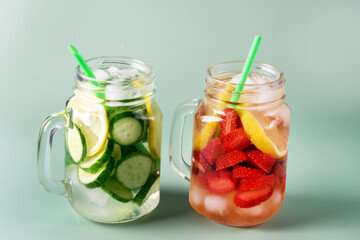 Variety of Cold Summer Drinks in Glass Jars Infused Detox Water with Cucumber Lemon and Strawberry Healthy Drink Green Background Horizontal