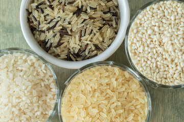 top view close up different types of rice. wild rice, sushi rice, shredded and steamed rice on a green wooden background. healthy food concept.