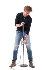 Young good-looking rock singer adjusting microphone stand height. Full body length isolated on...