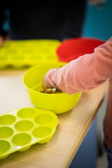 main d'une petite fille qui joue avec des jouets en plastique sur une table en bois