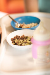 repas de bébé posé sur une chaise haute avec un biberon