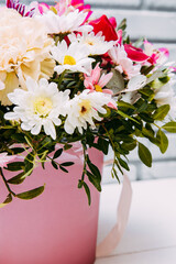 Delicate bouquet of different flowers in pink packaging. Square photo close-up