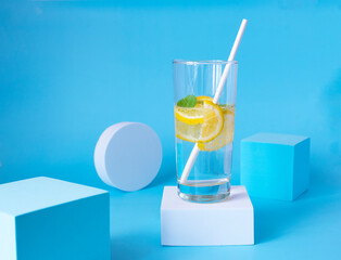 Lemonade on a blue background and a white podium. Refreshing summer drink with copy space