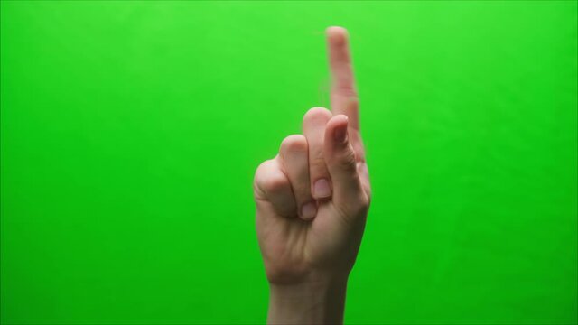 Close-up of a hand gesture on a green background, shooting a gesturing in studio, shaking finger at somebody, raising a threatening finger. 