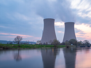 Nuclear power plant against sky by the river at sunset