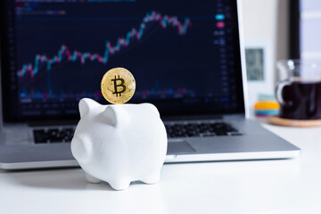 Trading or savings cryptocurrency with bitcoin and piggy bank and blur of chart price on computer.
